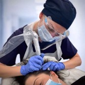 Medical trichologist performing a follicular unit extraction hair transplant procedure on a patient